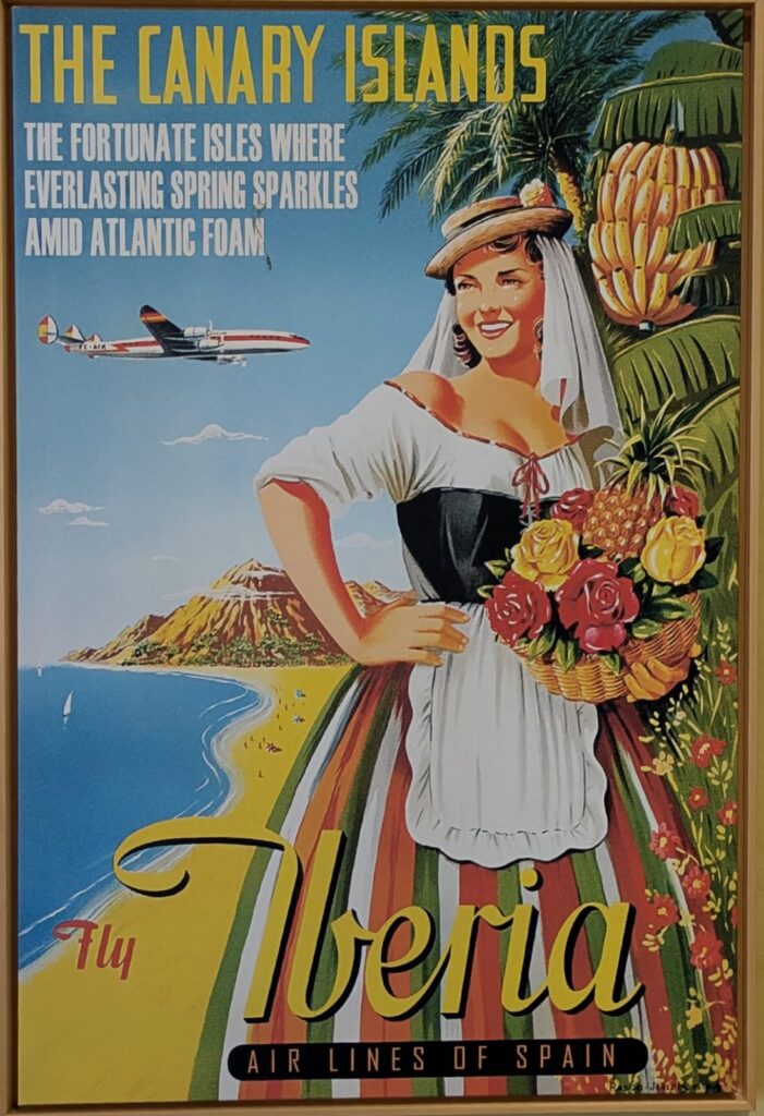 Cartel publicitario de estilo retro de la aerolínea Iberia, que muestra a una mujer con traje tradicional y una cesta de frutas frente a un paisaje costero con un avión sobrevolando.